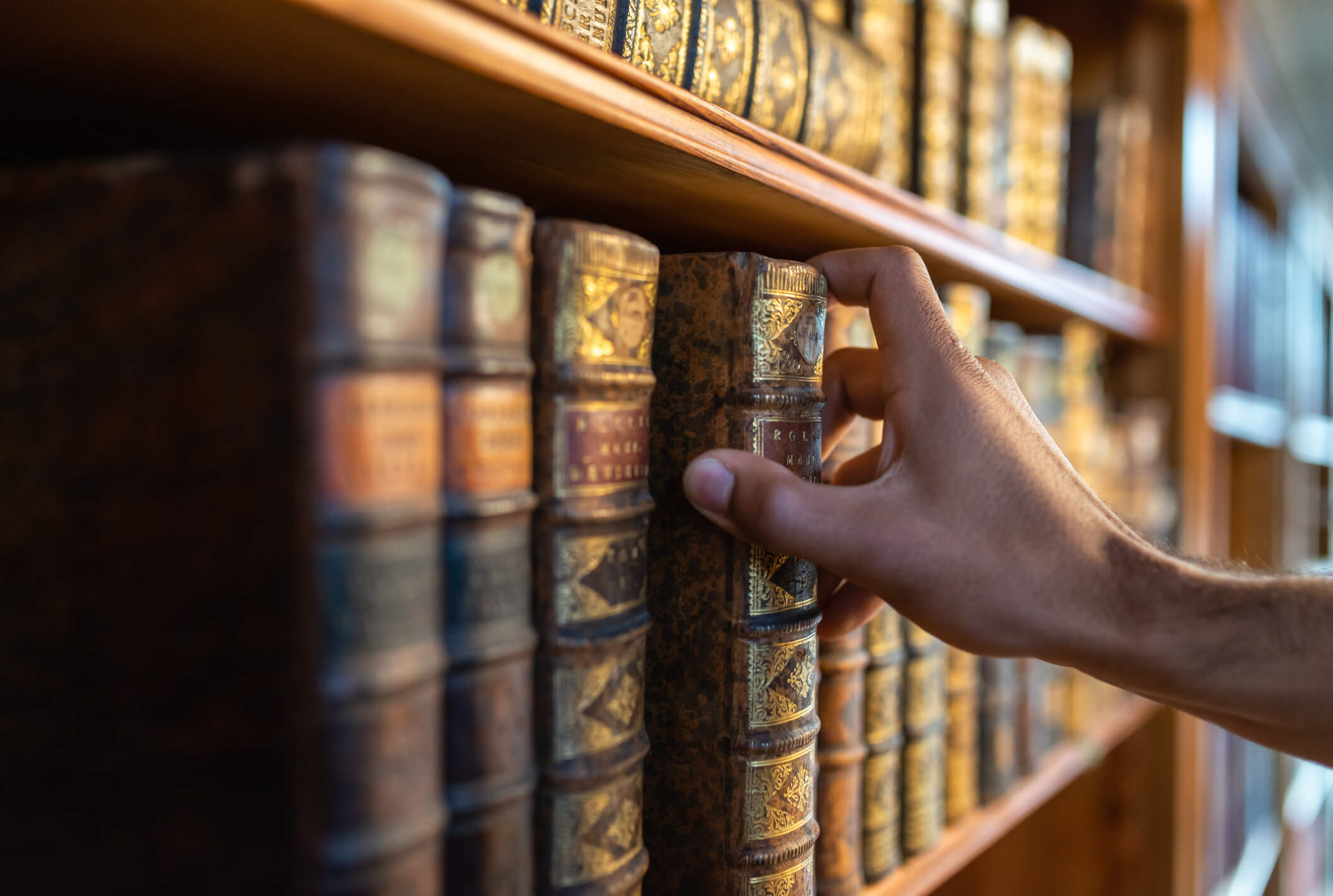 Hand-Grabbing-Antique-Book-from-Shelf-iStock-1134934443.jpg