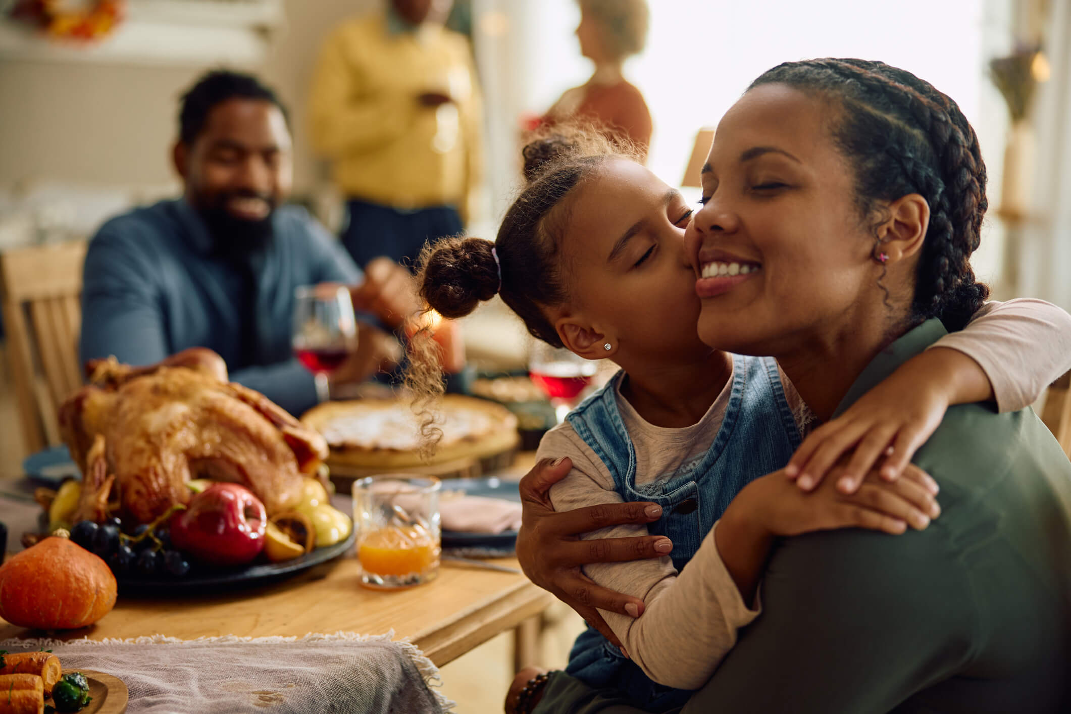 Family-at-Holiday-Meal-Girl-Kissing-Woman-iStock-1727475080.jpg